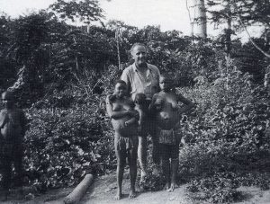 Alan Cooper (East 1926) with pygmies in the Congo. Cooper, a failed Kenyan coffee planter and three associates set out in April 1955 from Nairobi in a Morris Traveller to drive across Africa, through the Sahara Desert and Europe to London.  The poorly planned expedition was to end in failure and his death